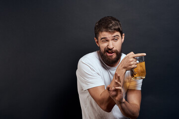 Man with a mug of beer in his hands emotions fun lifestyle white t-shirt dark isolated background