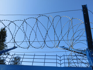 barbed wire against a clear blue sky, like a prison