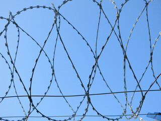 barbed wire against a clear blue sky, like a prison