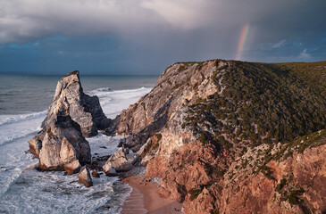 Portugal Ursa Beach at сoast of Atlantic Ocean. Rocks and waves at sand of coastline picturesque landscape.