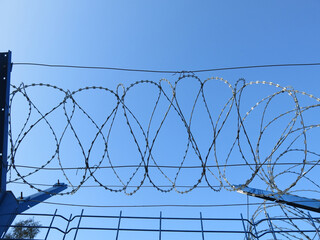 barbed wire against a clear blue sky, like a prison
