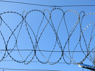 barbed wire against a clear blue sky, like a prison