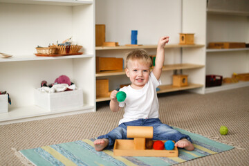 child toddler plays with balls and cylinders, developing sensory activities in montessori and earlier development of children, independence of babies