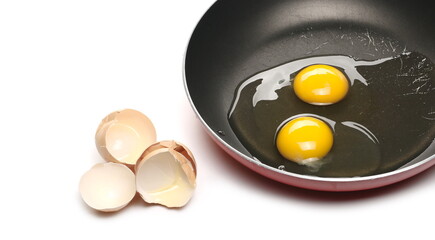 Raw eggs with yolk in frying pan and cracked shells isolated on white background