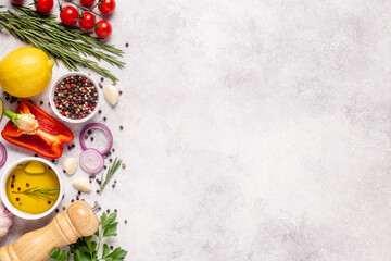 Herbs and condiments on light stone background.