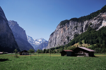 Fototapeta na wymiar Beautiful summer landscape with barn on green field, Swiss Alps Mountains.