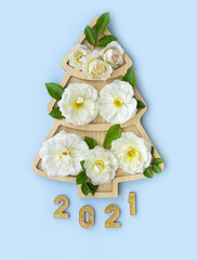 Christmas tree creative of white roses isolated on a blue background. The concept of an flowers Christmas tree.