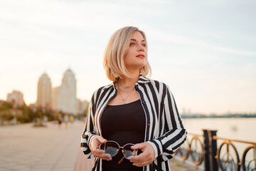 Fototapeta premium Outdoor portrait of happy young woman on city promenade.