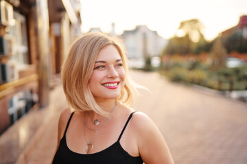 Outdoor portrait of happy young woman walking by city street.