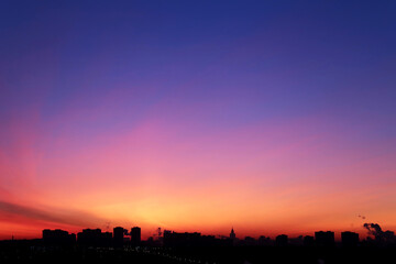 Sunrise over the city, scenic view. Pink-blue sky in soft colors sky above silhouettes of high-rise...