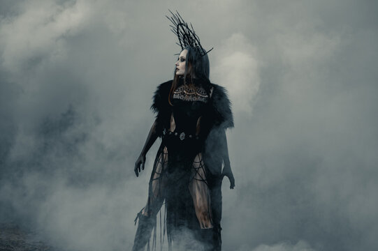 Woman in image of witch stands against smoke background.