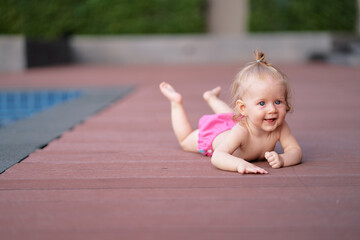 Little baby girl near swimming pool outdoors.