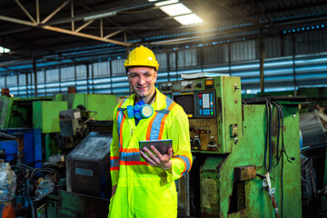 Factory engineer holding a tablet to control the operation of industrial machinery..