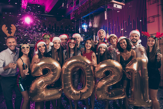 Photo portrait of big 2021 new year party with people holding golden balloons shampagne glasses with silly festive santa claus x-mas headwear