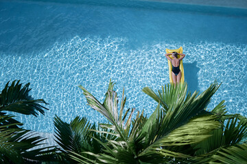 Enjoying suntan. Tropical vacation concept. Top view of young woman on the yellow air mattress in...
