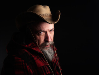 middle-aged man with a gray beard in a checkered red cloth jacket with cowboy hat