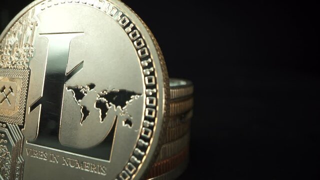 Gold crypto coin Lite coin in macro shot. Many other coins on the black surface with dark background. Blockchain technology. Currency of new life
