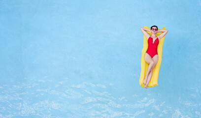 Enjoying suntan. Tropical vacation concept. Top view of young woman on the yellow air mattress in...