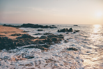 Beautiful sunset seascape with rock on sand beach.