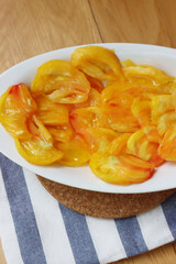 Pineapple tomatoes cut in slices on a white bowl on a wooden table. Pineapple tomato variety