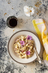 A plate full of butter gnocchi with malva flowers.