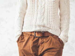 Woman in cable-knit white sweater with Scandinavian pattern and brown chinos trousers with leather...