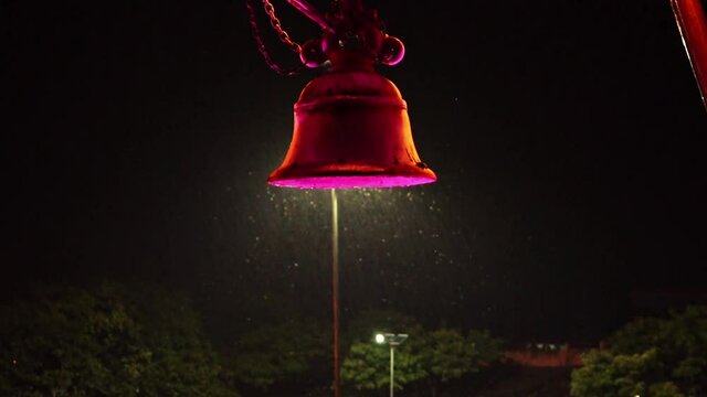 Swarm Of Insects Flying Around A Colorful Glowing Bell On A Rainy Night - close up