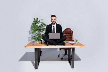 Full length photo of handsome business guy hold notebook knees good mood sitting table lotus yoga pose love his job wear blazer shirt pants shoes suit isolated grey background