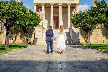 Obraz premium Beautiful wedding couple in Athens, Greece. Look at the classical architecture of University, the view from the back