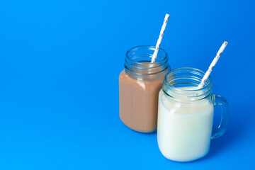 Glass jar with fresh milk against blue background