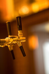 Shiny gold colored beer tap nozzles in a bar