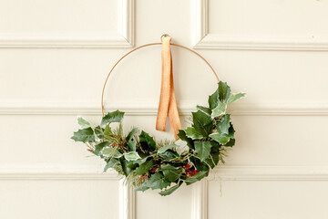 Christmas / New Year composition. Festive wreath of leaves, fir branches against white wall. Minimal winter holidays concept.