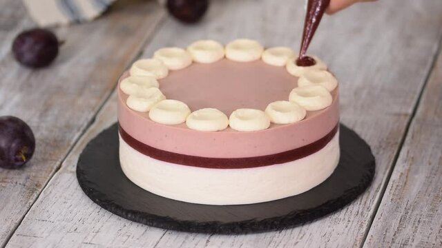 Pastry chef decorated a delicious plum mousse cake with jam.