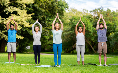 fitness, sport and healthy lifestyle concept - group of happy people doing yoga at summer park