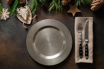 Christmas rustic home table setting with empty plate and xmas wooden decor on brown table. Top view, flat lay.