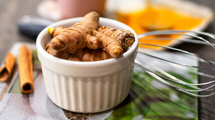 Heap of Turmeric roots in white bowl on table