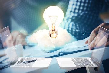 View of Bulb lamp idea concept icon on a futuristic interface with writing man's hand background. Double exposure.