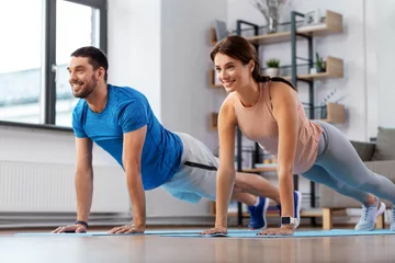 Poster sport, fitness, lifestyle and people concept - smiling man and woman exercising and doing plank at home © Syda Productions