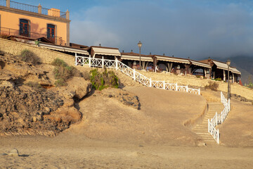 Obraz premium Wooden stairway path connecting the beach with the long promenade lined up with elegant restaurants, shops and entertainment, Playa del Duque, Adeje, Tenerife, Canary Islands, Spain