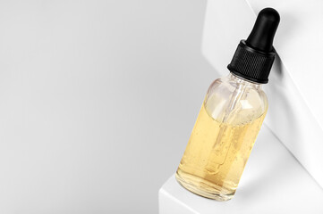 Serum in a transparent bottle with a pipette on a geometric white background. Cosmetic moisturizer...