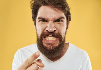 Bearded guy on a yellow isolated background gestures with his hands