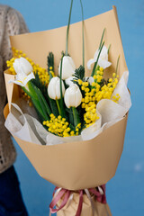Bouquet of flowers in beige package in hands.