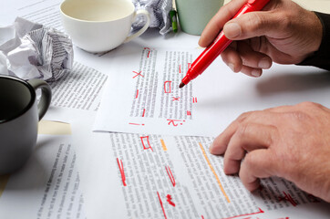 Lorem ipsum text.Process of proofreading.Man checking the text.Cups, documents abd man holding red marker - obrazy, fototapety, plakaty