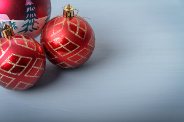 Three Christmas balls.
Three red balls for Christmas tree located in the upper left corner on a light blue wooden table. Space for text on the right.