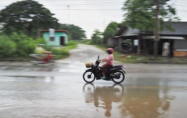 Fototapeta na wymiar A motorbike is running on a watery road on the road.