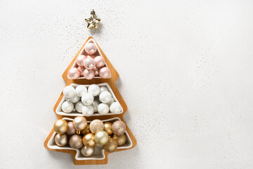 Fototapeta na wymiar Christmas greeting card with plate fir tree shaped with golden shiny baubles on white.