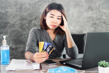 stress Asian woman with financial problem ,debt during covid-19 virus pandemic hand holding credit cards  