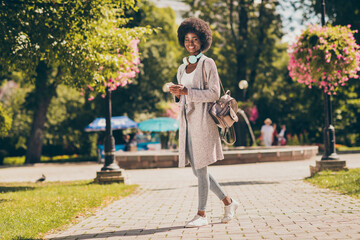 Full body photo of charming dark skin lady in green tree town center outside park hold cellphone wear sweater jeans © deagreez