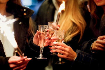 Caucasian young girls with champagne and lights on the street, cheerful company of girls and celebration, new year and christmas