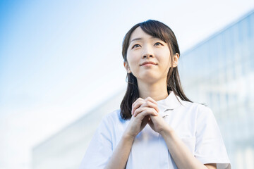 お祈りのポーズをする白衣の女性